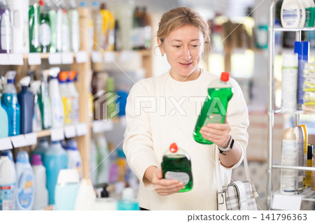 Adult woman chooses dishwashing detergent in store Adult woman chooses dishwashing detergent in store 141796363