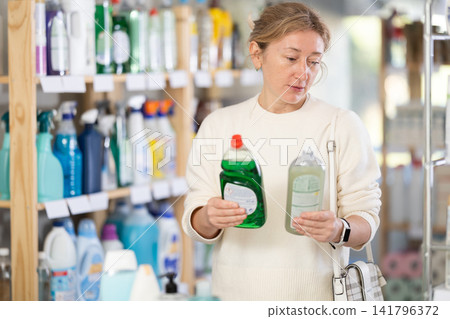 Adult woman chooses dishwashing detergent in store Adult woman chooses dishwashing detergent in store 141796372