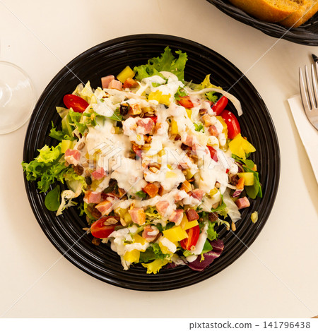 spanish lettuce salad with sauce and bacon in black plate for dinner spanish lettuce salad with sauce and bacon in black plate for dinner 141796438