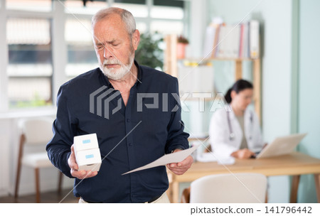 Elderly man with package of pills and prescription leaves medical clinic Elderly man with package of pills and prescription leaves medical clinic 141796442