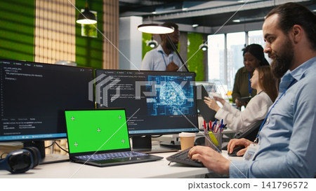 Admin in office using isolated screen laptop, automating repetitive tasks with AI scripts. IT expert using artificial intelligence on chroma key device to speed up feature implementation, camera A Admin in office using isolated screen laptop, automating repetitive tasks with AI scripts. IT expert using artificial intelligence on chroma key device to speed up feature implementation, camera A 141796572