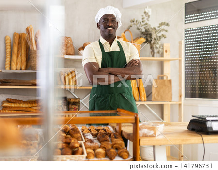 Cheerful man baker at counter in bakery Cheerful man baker at counter in bakery 141796731