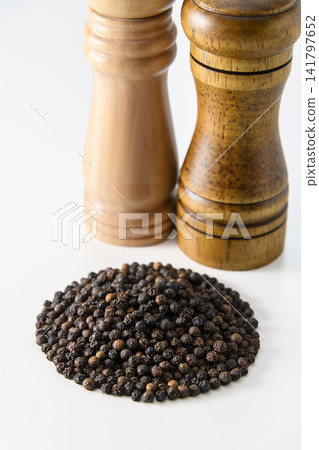 餐桌上擺放著黑胡椒粉和木製胡椒研磨器。 餐桌上擺放著黑胡椒粉和木製胡椒研磨器。 141797652