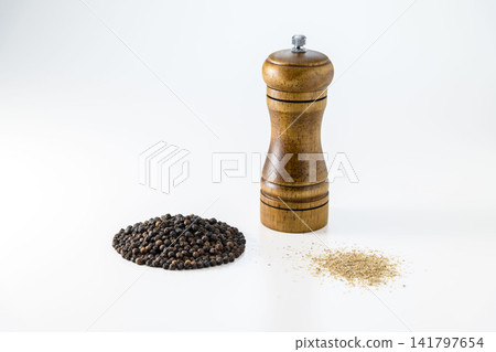 黑胡椒粒、胡椒粉和木製胡椒研磨器整齊地擺放在一起。 141797654