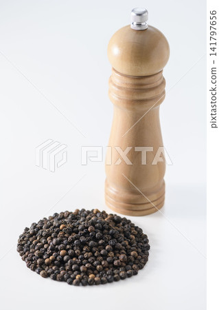 A still life combination of black pepper and a pepper mill. A still life combination of black pepper and a pepper mill. 141797656