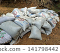 Farm feed sacks piled on rustic ground, essential poultry supplies storage outdoors 141798442