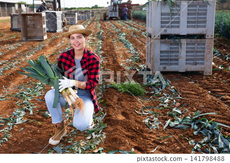 Portrait of positive girl farmer with fresh leek on field Portrait of positive girl farmer with fresh leek on field 141798488