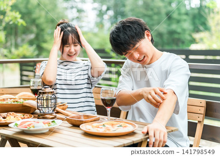 A couple is having trouble with insect bites while eating outdoors. A couple is having trouble with insect bites while eating outdoors. 141798549