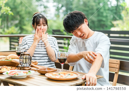 A couple is having trouble with insect bites while eating outdoors. A couple is having trouble with insect bites while eating outdoors. 141798550