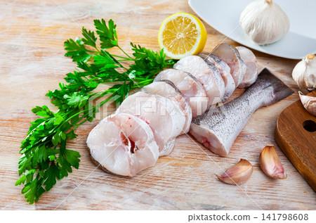 Raw steaks of hake with lemon and greens ready for cooking Raw steaks of hake with lemon and greens ready for cooking 141798608
