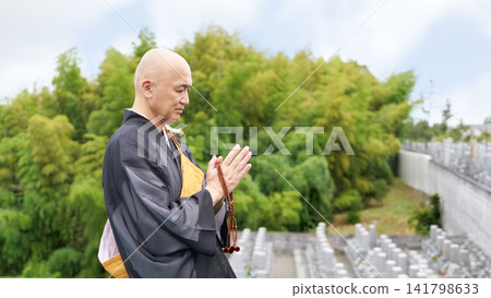 A monk's profile as he quietly offers a prayer in a cemetery. A monk's profile as he quietly offers a prayer in a cemetery. 141798633