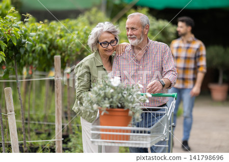 Senior couple of with shopping cart walks through floral shopping center Senior couple of with shopping cart walks through floral shopping center 141798696
