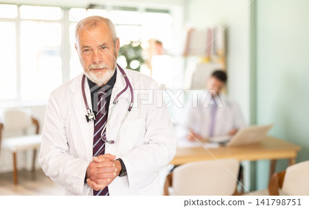 Elderly male doctor standing in medical office Elderly male doctor standing in medical office 141798751