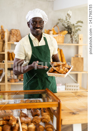 Portrait of positive man bakery worker with croissants Portrait of positive man bakery worker with croissants 141798785