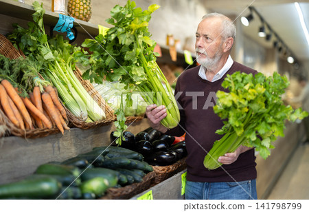 Elderly man chooses celery for purchase in greengrocer shop 141798799