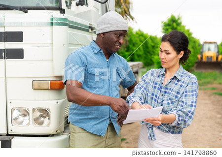 Delivery courier invites farmer to sign documents near truck Delivery courier invites farmer to sign documents near truck 141798860