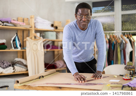 African American man tailor draw dress pattern of product on paper African American man tailor draw dress pattern of product on paper 141798861