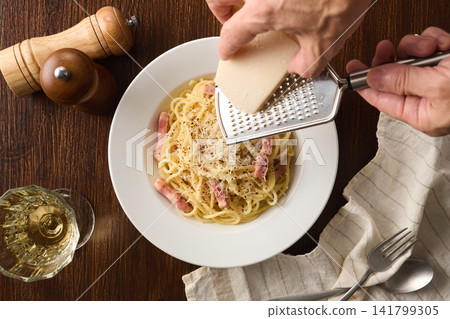 Sprinkle Parmesan cheese over the carbonara. Sprinkle Parmesan cheese over the carbonara. 141799305