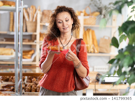 Portrait of happy female customer holding a baked pie in hands Portrait of happy female customer holding a baked pie in hands 141799365