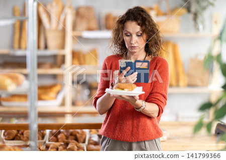 Woman photographing a sandwich in a bakery Woman photographing a sandwich in a bakery 141799366