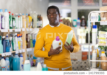 Before buying in household shop, African male customer choose liquid detergent Before buying in household shop, African male customer choose liquid detergent 141799393