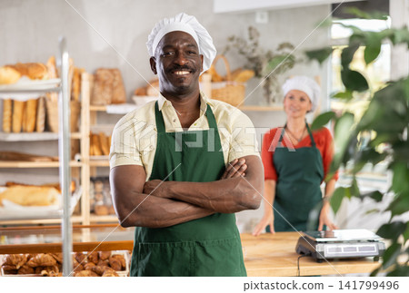 Portrait of professional smiling male baker in uniform in bakery Portrait of professional smiling male baker in uniform in bakery 141799496