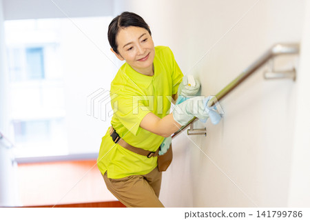 一名五十多歲的女員工正在清潔樓梯扶手。 一名五十多歲的女員工正在清潔樓梯扶手。 141799786