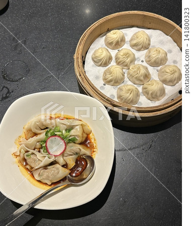 Steamed xiaolongbao dumplings with delicate thin skin, slightly translucent top folds, and savory soup filling inside, highlighting their soft texture and freshly steamed appearance in close-up detail Steamed xiaolongbao dumplings with delicate thin skin, slightly translucent top folds, and savory soup filling inside, highlighting their soft texture and freshly steamed appearance in close-up detail 141800323