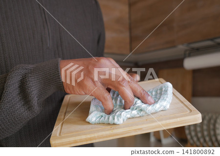 Hand holding a towel on a wooden cutting board Hand holding a towel on a wooden cutting board 141800892