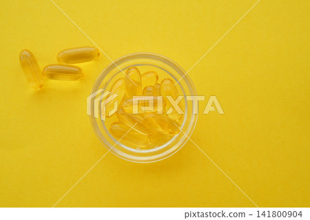 fish oil capsules in a bowl on a bright yellow background fish oil capsules in a bowl on a bright yellow background 141800904