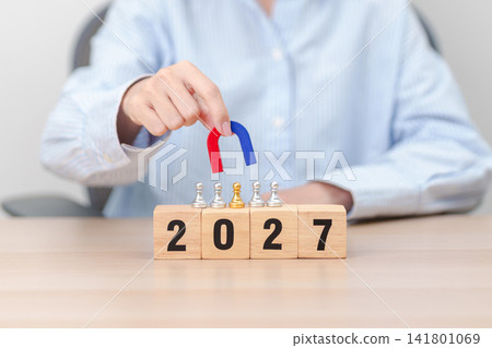 hand holding magnet and pulling man chess figure from the crowd employee with 2027 Year block. Human resource management, Recruitment, Teamwork, strategy, toxic people and leadership Concepts hand holding magnet and pulling man chess figure from the crowd employee with 2027 Year block. Human resource management, Recruitment, Teamwork, strategy, toxic people and leadership Concepts 141801069