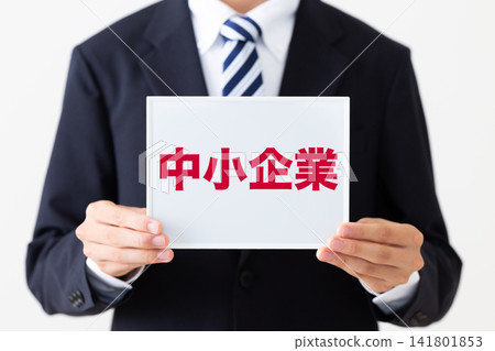 A young businessman in a business suit holding a whiteboard at a small business. A young businessman in a business suit holding a whiteboard at a small business. 141801853