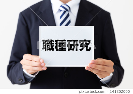 一位身穿西裝的年輕商人手持白板,正在進行求職研究。 一位身穿西裝的年輕商人手持白板,正在進行求職研究。 141802000