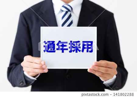 A young male businessman in a business suit holding a whiteboard for year-round recruitment. A young male businessman in a business suit holding a whiteboard for year-round recruitment. 141802288
