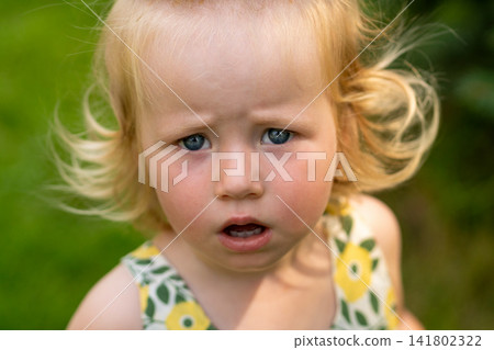 Close Portrait of Uncertain Blonde Toddler Outdoors Close Portrait of Uncertain Blonde Toddler Outdoors 141802322
