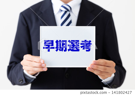 A young businessman in a business suit holding a whiteboard for early selection. A young businessman in a business suit holding a whiteboard for early selection. 141802427