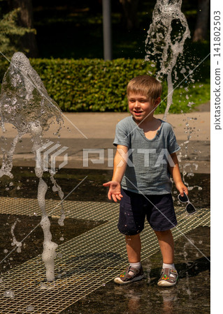 Smiling Young Boy Standing Between Outdoor Fountain Jets Smiling Young Boy Standing Between Outdoor Fountain Jets 141802503