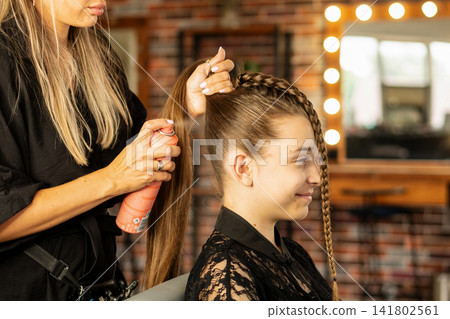 Hairstylist Applying Hair Spray To Teen Client Ponytail In Salon Hairstylist Applying Hair Spray To Teen Client Ponytail In Salon 141802561