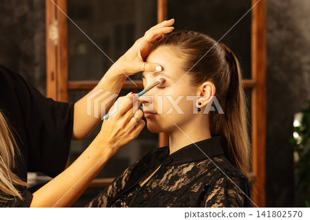 Makeup Artist Blending Eyeshadow On Teen Client In Salon Makeup Artist Blending Eyeshadow On Teen Client In Salon 141802570
