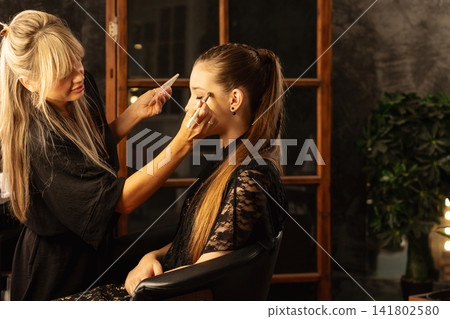 Makeup Artist Refining Teen Client Eye Makeup In Salon Makeup Artist Refining Teen Client Eye Makeup In Salon 141802580