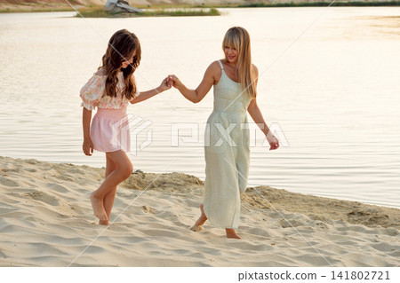 Mother Adjusting Daughter Sun Hat In Sandy Landscape Mother Adjusting Daughter Sun Hat In Sandy Landscape 141802721