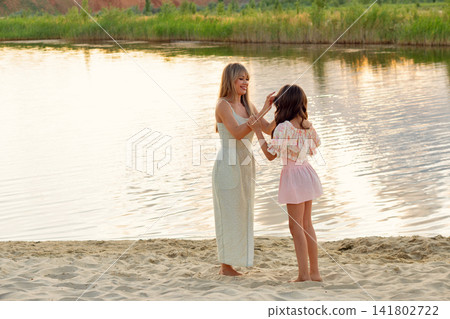 Mother Adjusting Daughter Sun Hat In Sandy Landscape Mother Adjusting Daughter Sun Hat In Sandy Landscape 141802722