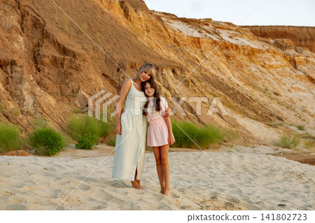 Mother Adjusting Daughter Sun Hat In Sandy Landscape 141802723