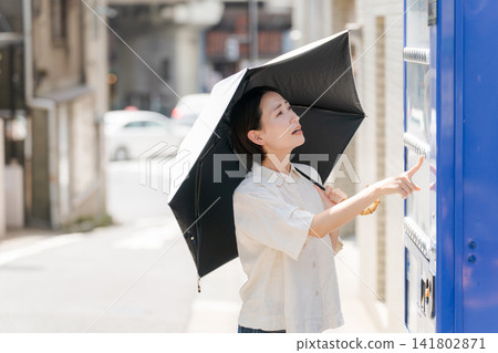 A woman buying a drink from a vending machine on a hot day. A woman buying a drink from a vending machine on a hot day. 141802871