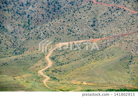 Aerial view shows rugged, arid hills with two dirt paths Aerial view shows rugged, arid hills with two dirt paths 141802913