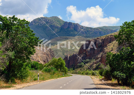 Scenic road cutting through rugged mountainous terrain with dense greenery Scenic road cutting through rugged mountainous terrain with dense greenery 141802976