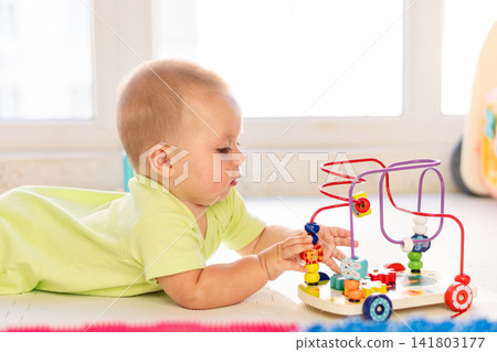 Infant Boy Practices Fine Motor Skills With Bead Maze Infant Boy Practices Fine Motor Skills With Bead Maze 141803177