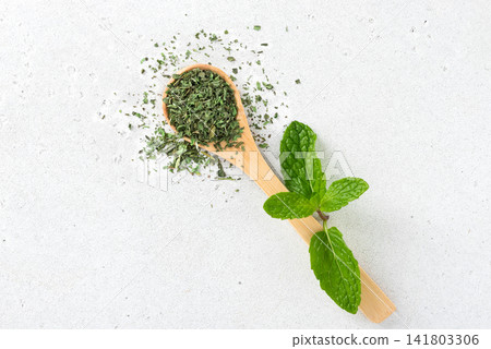 Dried mint leaves in wooden spoon with fresh mint on white background. Herbal medicine. Herbal tea. Dried mint leaves in wooden spoon with fresh mint on white background. Herbal medicine. Herbal tea. 141803306