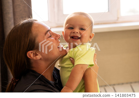 Baby Boy Touches Mother Chin During Playful Window Moment 141803475