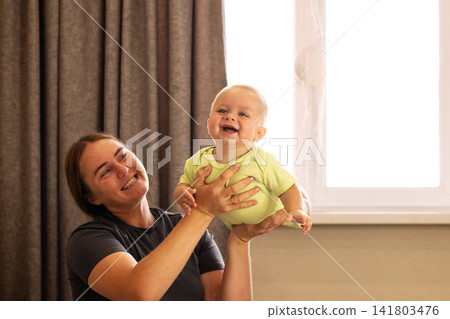 Baby Boy Touches Mother Chin During Playful Window Moment 141803476
